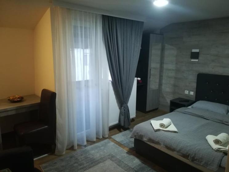 a bedroom with a bed and a window with white curtains at Prenoćište Day Holiday in Smederevo
