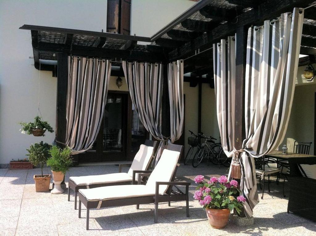 un patio con sedie e tende bianche e fiori di Luxury Villa Near Venice in the Prosecco Region a San Donà di Piave