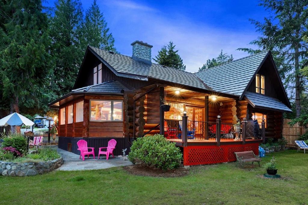 Union Bay Log Home في Union Bay: كابينة خشبية مع كراسي وردية في الفناء