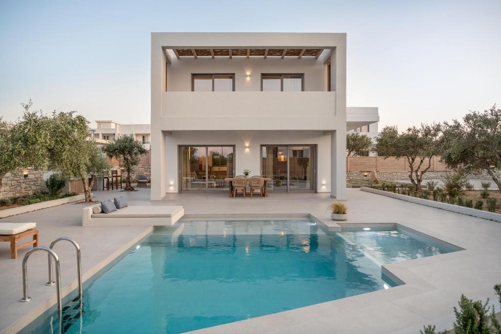 a villa with a swimming pool in front of a house at Anthos Villas - Chania in Tavronitis