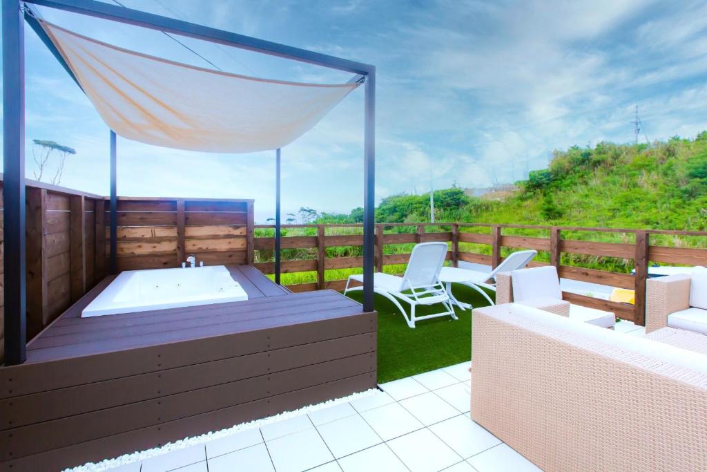 eine Terrasse mit einem Whirlpool und zwei weißen Stühlen in der Unterkunft The Moves -CinemaVilla- - Vacation STAY 12376v in Shushi