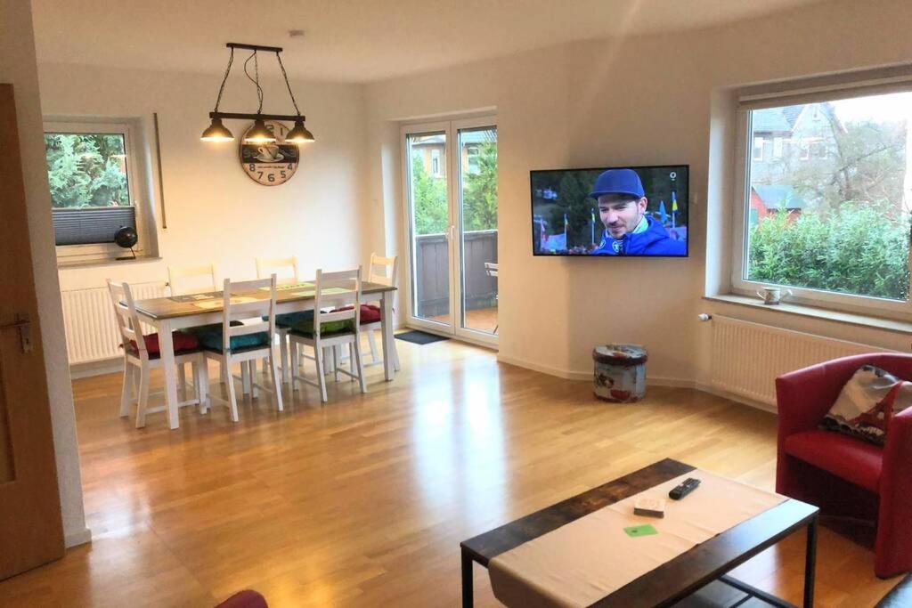 a living room with a table and a tv on the wall at EXKLUSIVE Ferienwohnung in Einbeck, 3 Schlafzimmer mit Balkon! in Einbeck