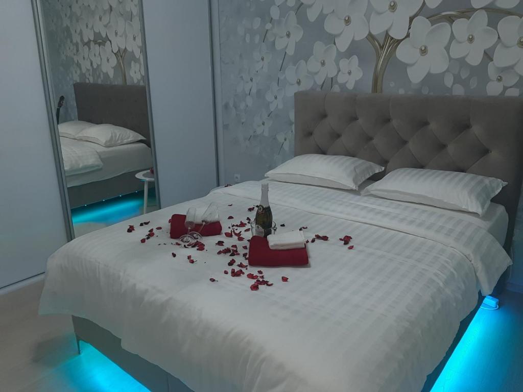 a bedroom with a white bed with roses on it at Apartman Akik 2 in Šabac