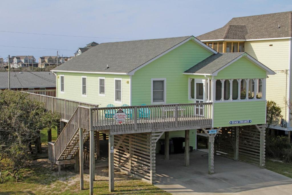 a green house with a wooden deck in front of a house at Beach Dreamer #4-BB in Buxton