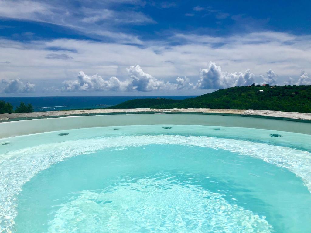 bañera de hidromasaje con agua azul y océano en Villa Solstice, en Le Marin
