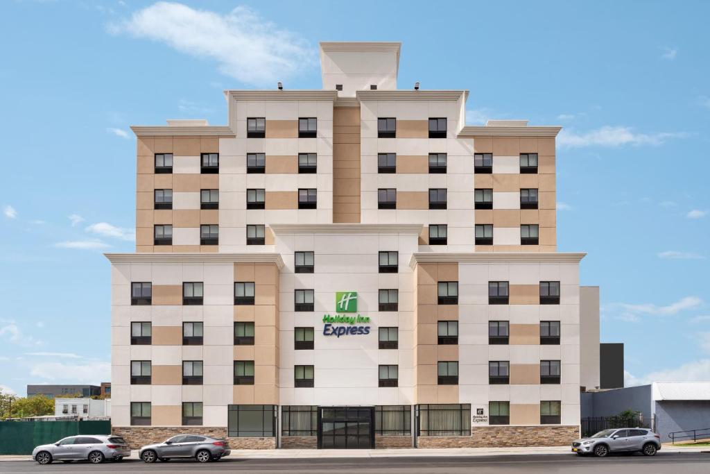 皇后區的住宿－Holiday Inn Express - Jamaica - JFK AirTrain - NYC, an IHG Hotel，前面有汽车停放的建筑