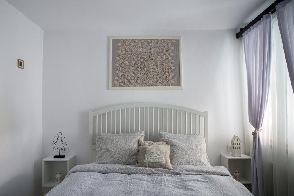 a white bedroom with a bed with gray pillows at Apartament Agnes in Braşov