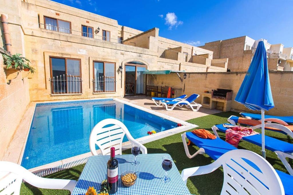 una piscina con sillas, mesa y sombrilla en Ta Danjela 4 bedroom Villa with private pool, en Xagħra
