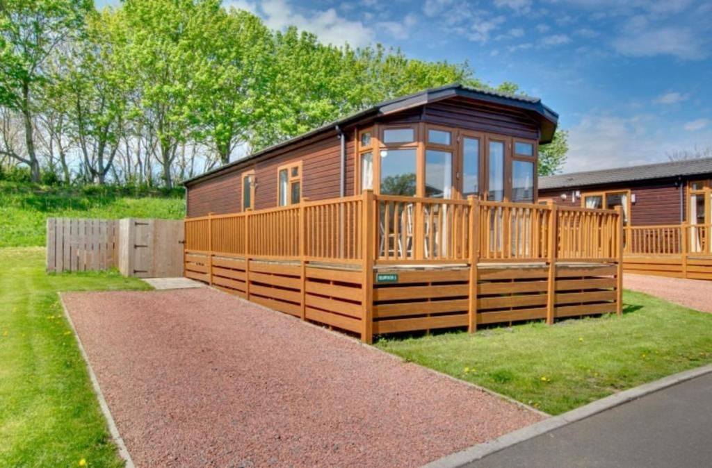 a large wooden cabin with a large deck at Stunning 3-Bed Hot Tub Lodge Northumberland in Felton