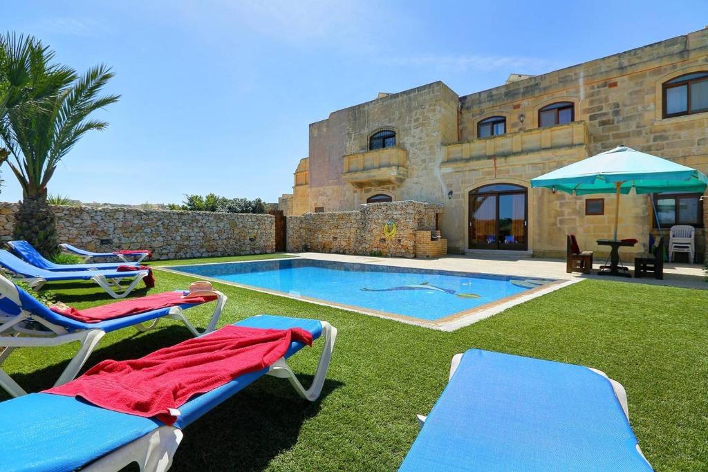 une villa avec une piscine et deux chaises longues dans l'établissement Villa Savona 3 Bedroom Villa with private pool, à Ix-Xagħra
