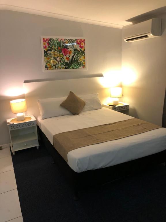 a bedroom with a large bed with two lamps at Motel Mt Gravatt in Brisbane