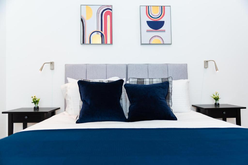 a bedroom with a blue and white bed with two tables at Absolute Stays at The Ziggurat - St Albans-High Street- Near Luton Airport - St Albans Abbey Train station -Close to London- Harry Potter World - The Odyssey Cinema-Contractors -London Road-Business-Leisure in Saint Albans