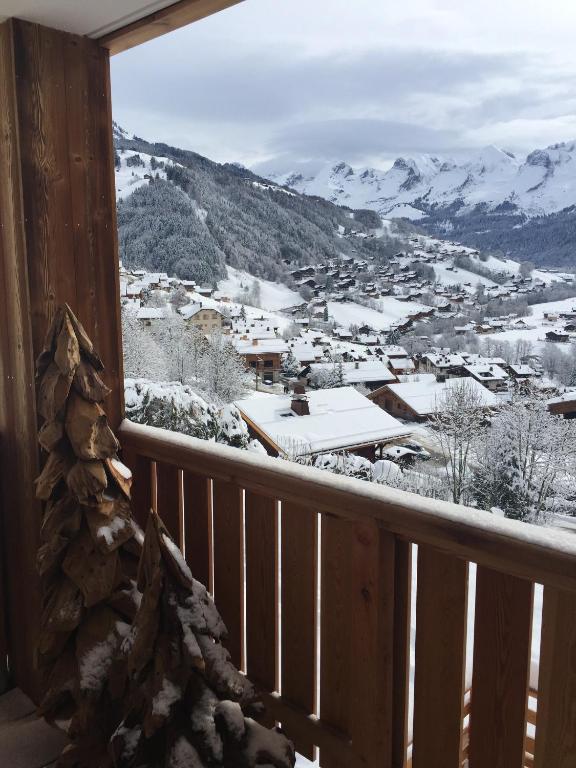 d'un balcon offrant une vue sur la ville dans la neige. dans l'établissement Appartement moderne à Le Grand-Bornand 70 m² avec vue montagne, au Grand-Bornand