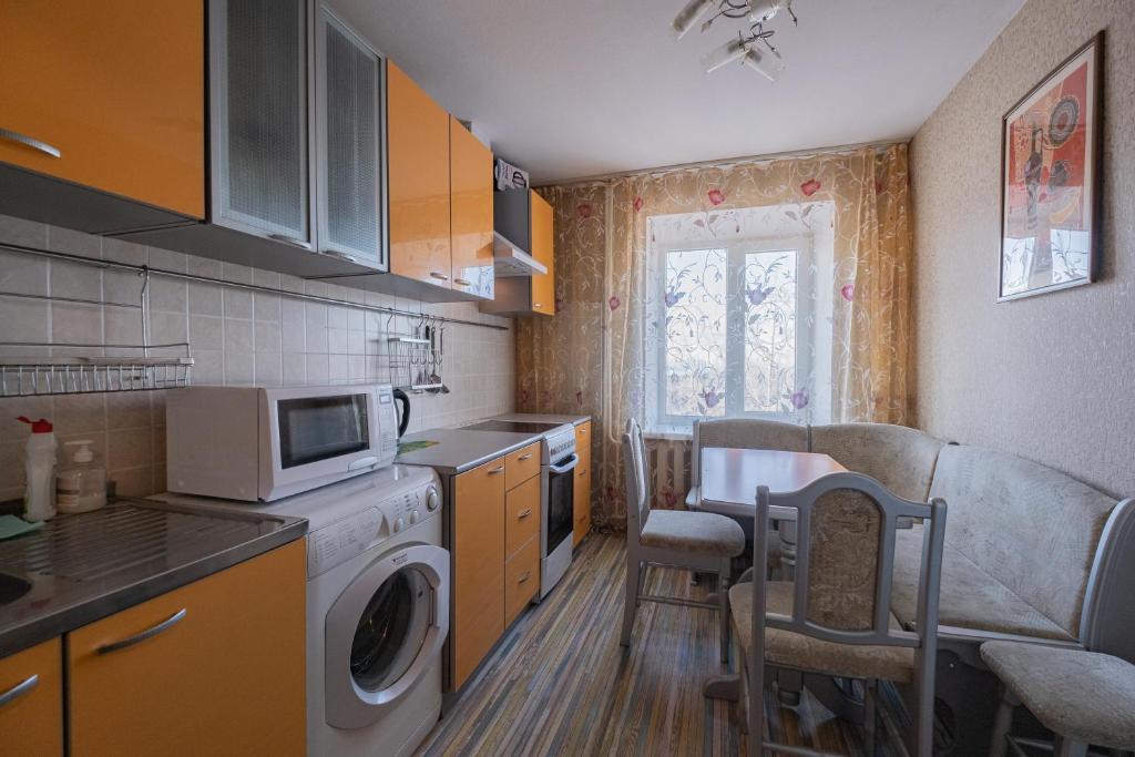 トムスクにあるАпартаменты Красноармейская 135のキッチン(洗濯機、テーブル、椅子付)