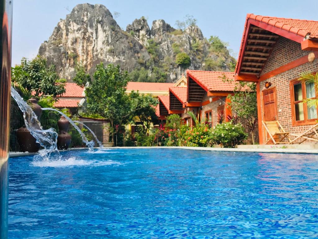 a pool with a waterfall in front of a resort at Tam Coc Friendly Homestay in Ninh Binh