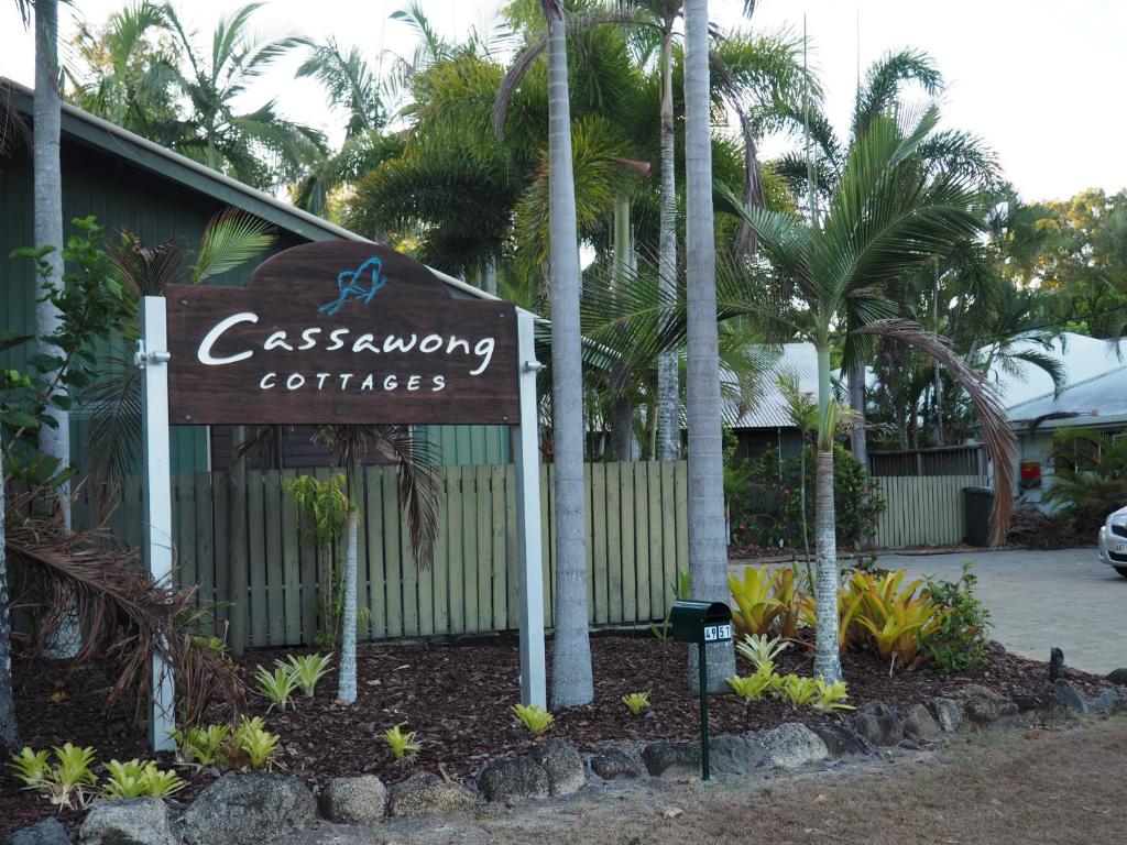 a sign in front of a building with palm trees at Cassawong Cottages in Mission Beach