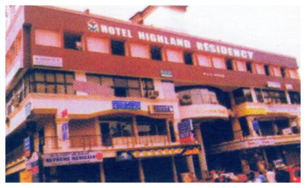 um edifício alto com pessoas à frente dele em HOTEL HIGHLAND RESIDENCY em Mangalore