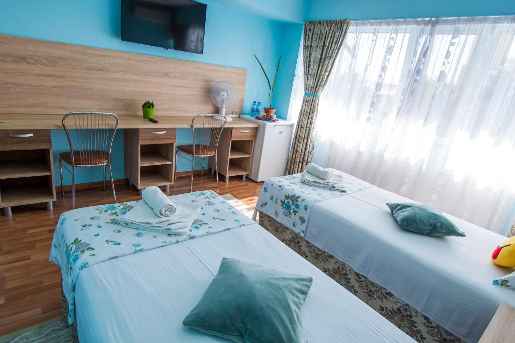um quarto com 2 camas, uma secretária e uma janela em Casa Paul em Galaţi