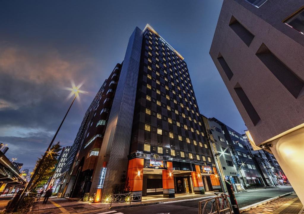 um edifício alto numa rua da cidade à noite em APA Hotel Akihabara Ekikita em Tóquio