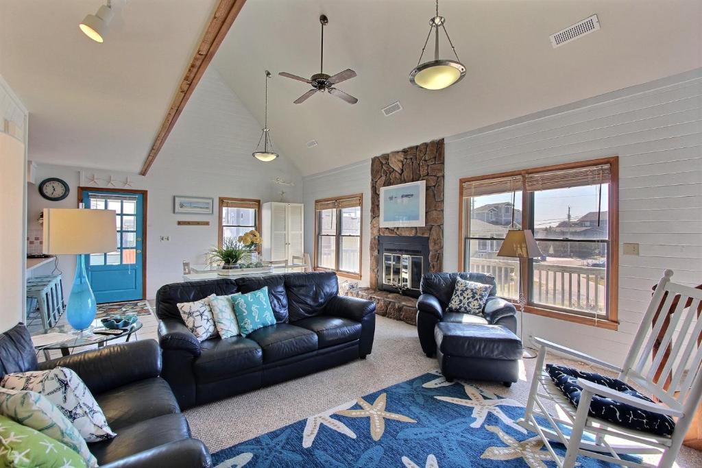 a living room with a leather couch and chairs at AVHC41 Outrigger Cottage on Hatteras Island in Avon