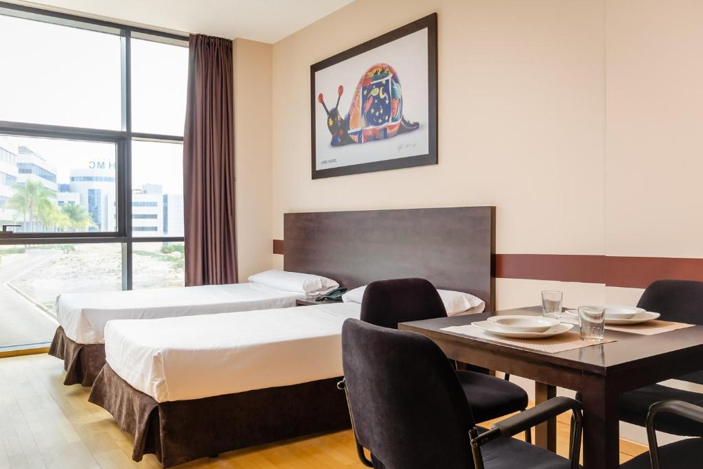 a hotel room with two beds and a table and chairs at Aparthotel Wellness in Paterna