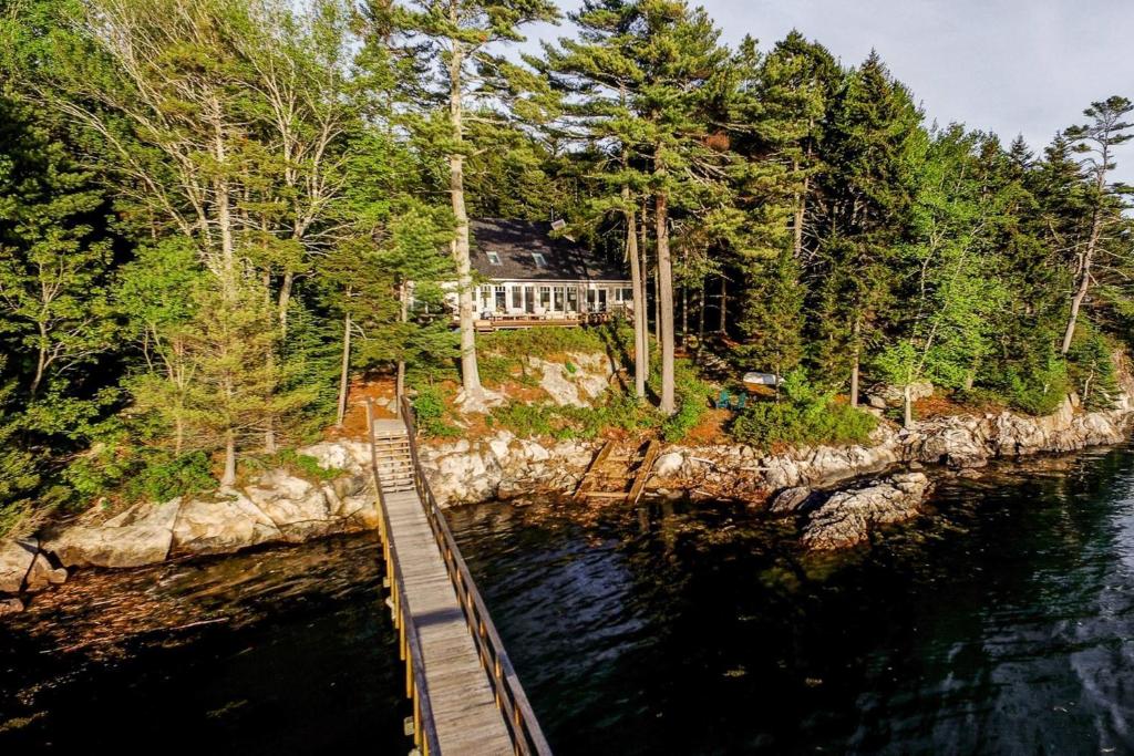 uma ponte de madeira sobre um corpo de água com uma casa em Maine Waterfront Luxury Retreat 