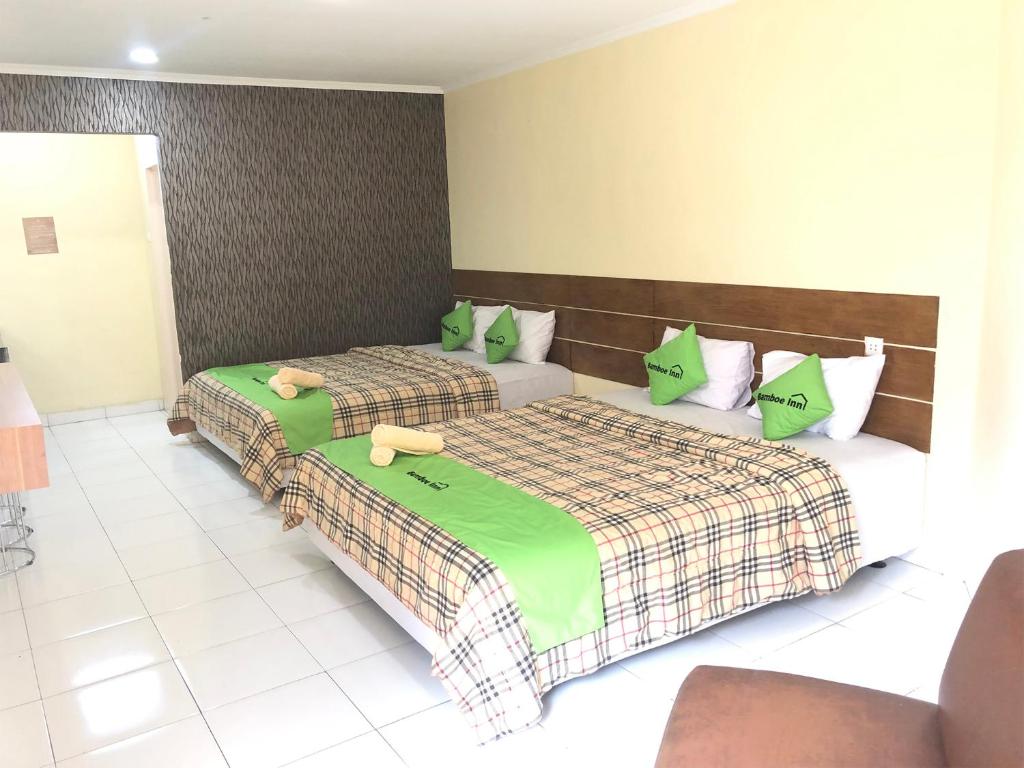een slaapkamer met 2 bedden en groene kussens bij Bamboe Inn 2 Homestay in Tanjungkarang