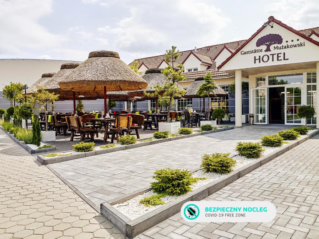 un hotel con un patio con mesas y sillas en Hotel Mużakowski en Łęknica