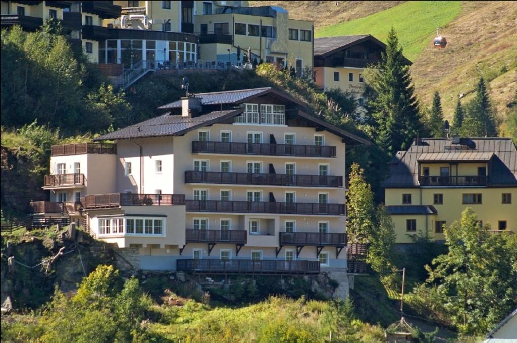ein großes weißes Gebäude auf einem Hügel mit Häusern in der Unterkunft Alpenhof by AlpenTravel in Bad Gastein
