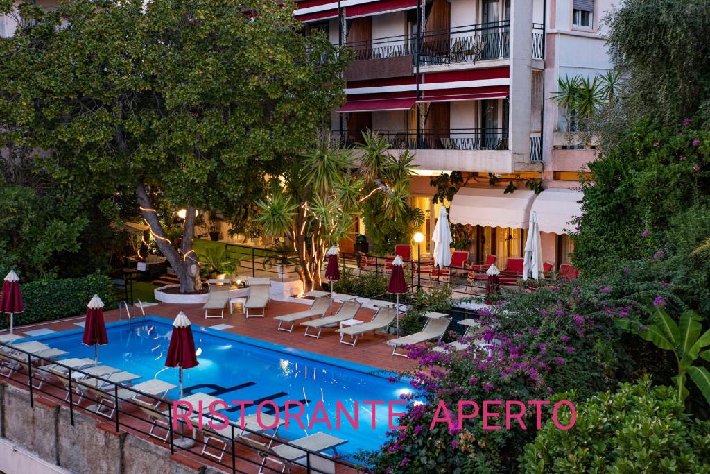 uma piscina com cadeiras e guarda-sóis ao lado de um hotel em Hotel Principe em Sanremo
