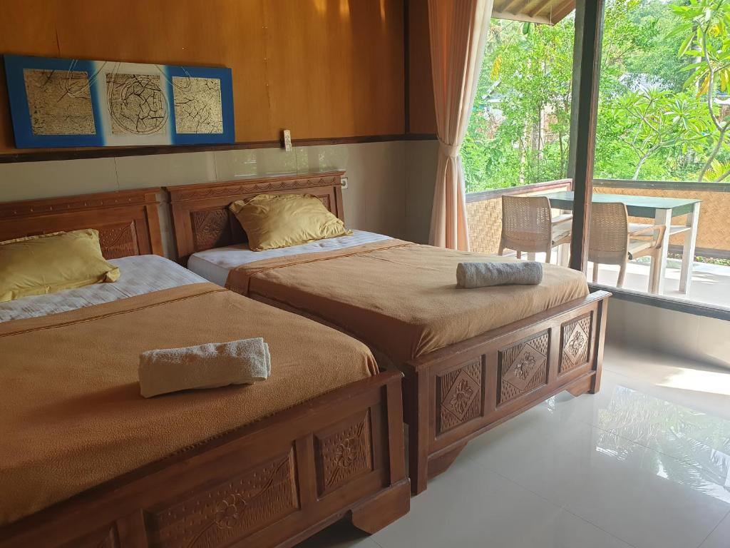 two beds in a room with a window at Kulkul Bungalow in Nusa Penida