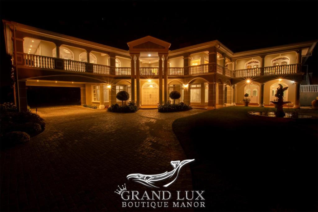 een groot herenhuis 's nachts met een bord dat zegt grand lux boutique manager bij Grand Lux Boutique Manor in Hermanus