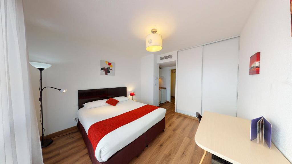 a bedroom with a bed and a desk in it at Alezan Hôtel & Résidence in Toulouse