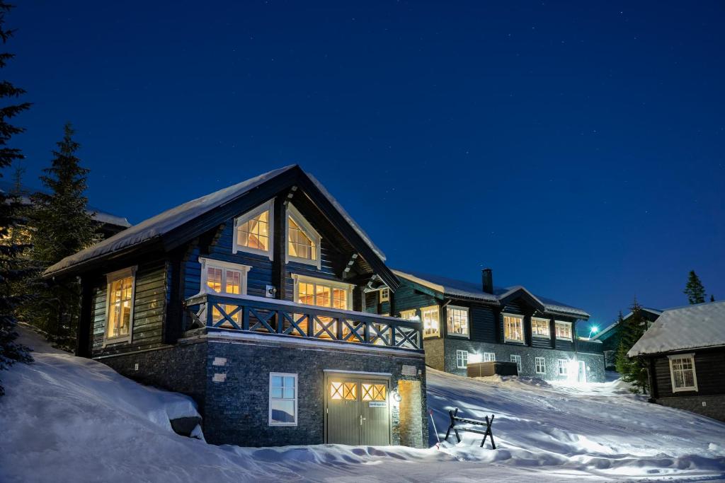 une grande maison dans la neige la nuit dans l'établissement Mosetertoppen Panorama anneks 3B, à Hafjell