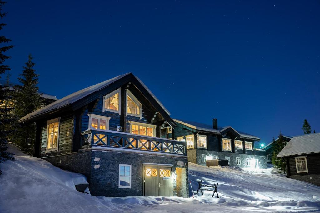 una casa grande en la nieve por la noche en Mosetertoppen Panorama anneks 3B, en Hafjell