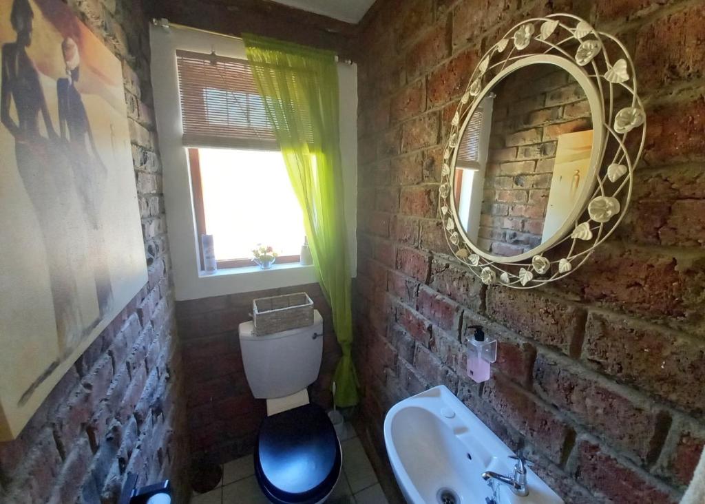 uma casa de banho em tijolo com um lavatório e um espelho. em Eagle Falls Country Lodge & Adventures em Buffelsdrif