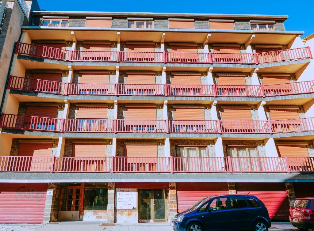 a car parked in front of a building with red balconies at Kione Calgary in Pas de la Casa