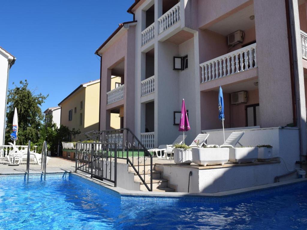 a hotel with a swimming pool in front of a building at Apartments Tatarovic in Malinska