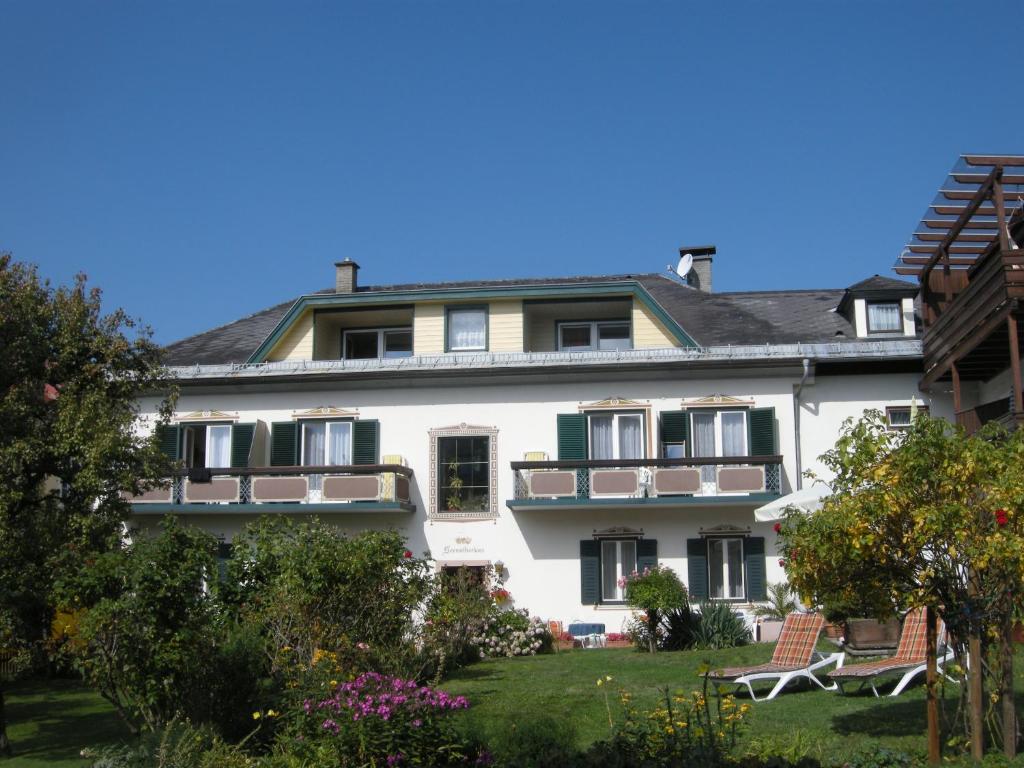 a large white building with two chairs in the yard at Seemüllnerhaus in Millstatt