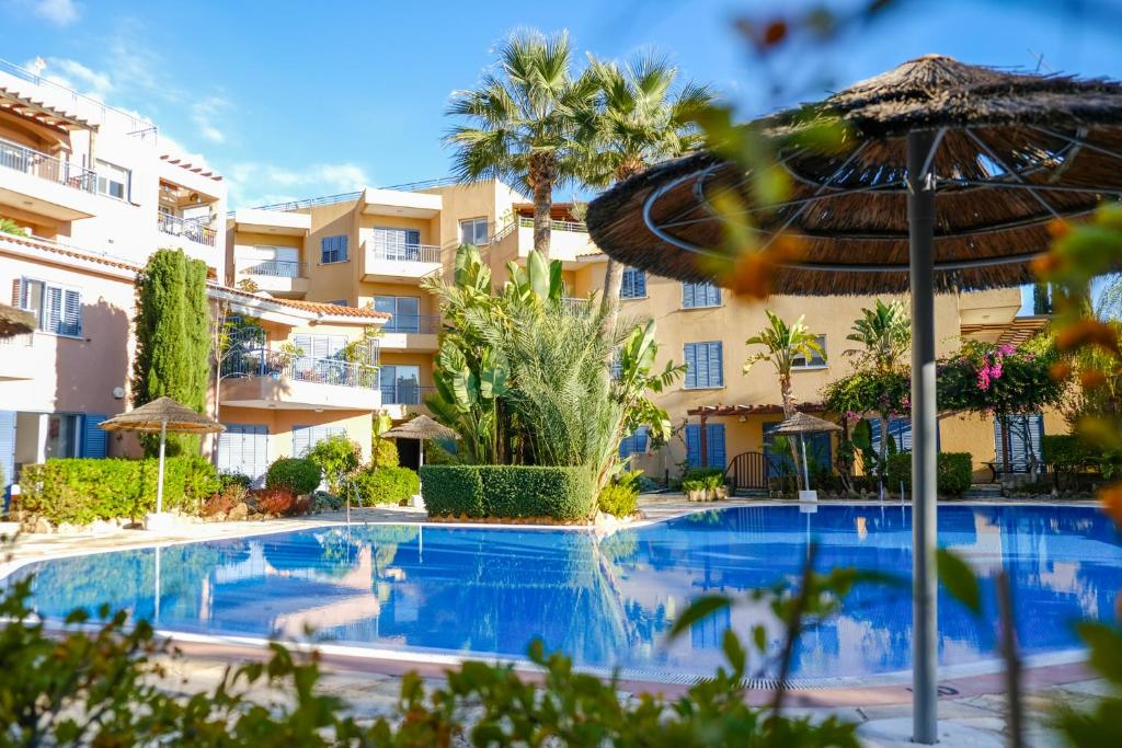 a swimming pool in front of a building with an umbrella at Zero Zero 2 in Peyia