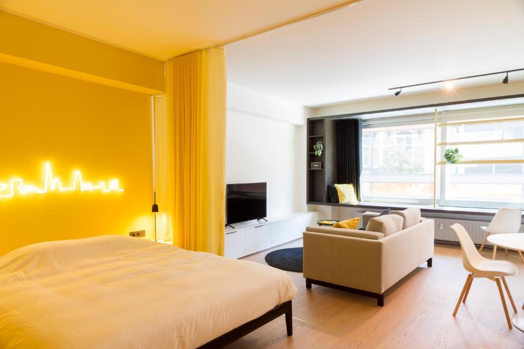 a bedroom with yellow walls and a bed and a couch at Hopland in Antwerp