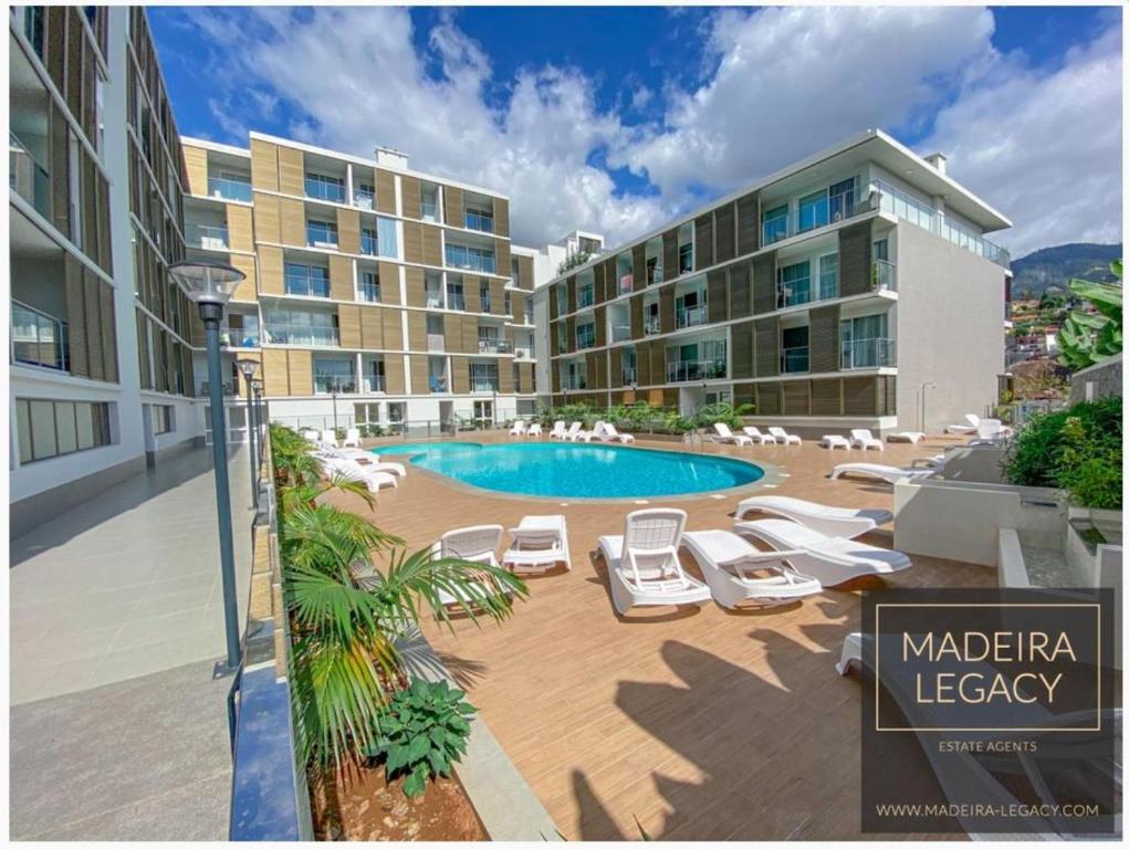 a hotel with a pool and chairs and a building at Madalenas Palace - Sunrise in Funchal