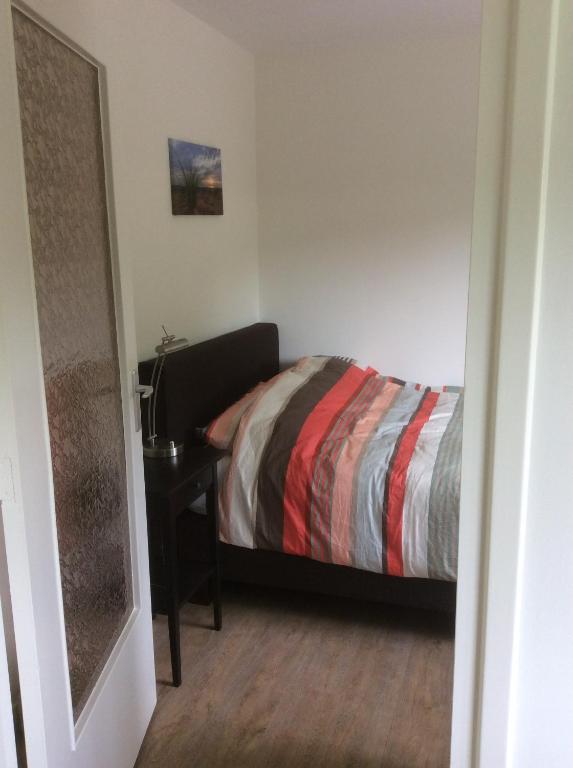 ein Schlafzimmer mit einem Bett und einem Nachttisch mit einem Tisch in der Unterkunft Vakantiehuisje vlakbij de duinen in Oostvoorne