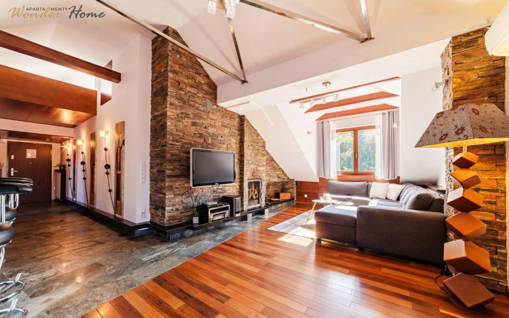 a living room with a brick wall and a couch at Wonder Home - Apartament Cud Malina z kominkiem, klimatyzacją i widokiem na Karkonosze in Karpacz