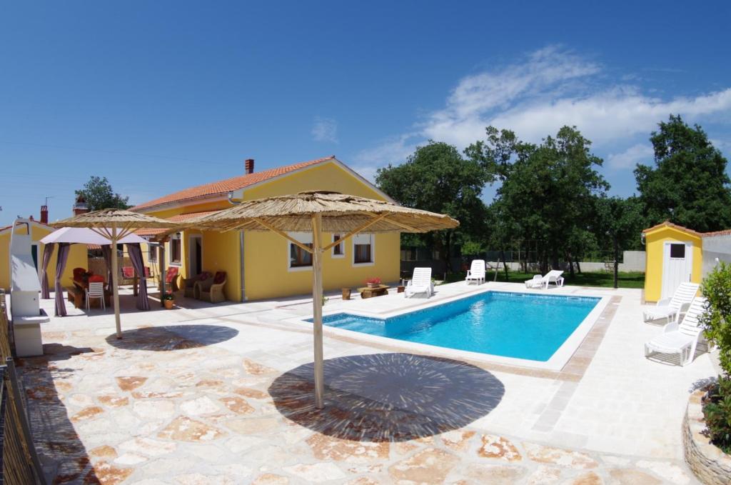 a swimming pool with an umbrella and a house at House Oliva, Sveti Kirin in Svetvinčenat