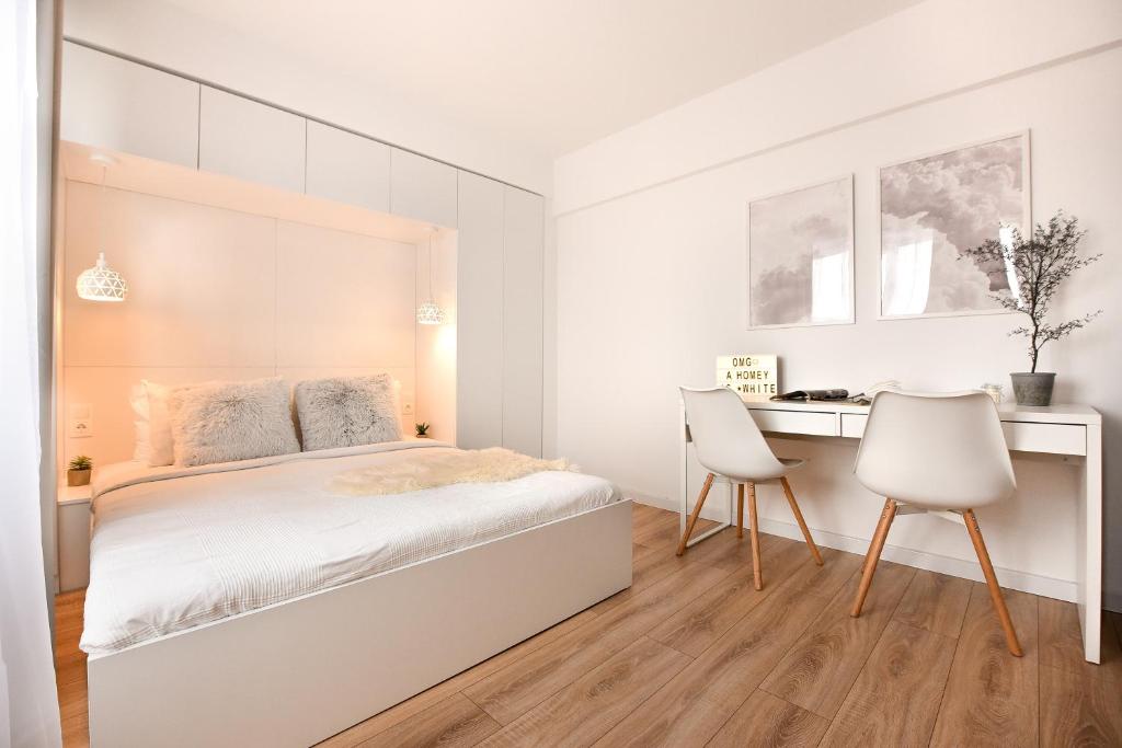 a white bedroom with a bed and a desk at WHITE HAVEN - Calea Victoriei Studio in Bucharest