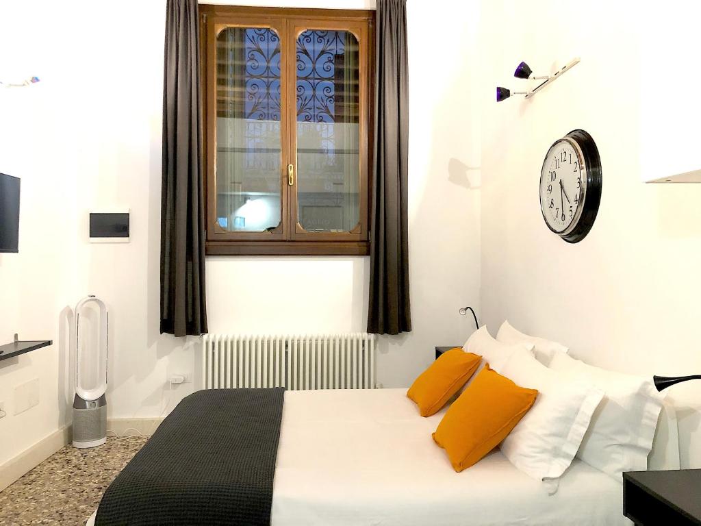 um quarto com uma cama com almofadas amarelas e um relógio em Residenza Pedrotti em Vicenza