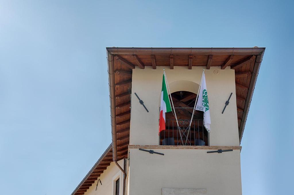 una torre con due bandiere sul lato di un edificio di Residenza Cappelli - Affittacamere a San Demetrio neʼ Vestini