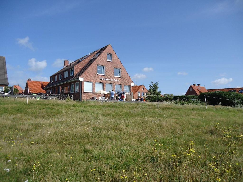 una casa grande en un campo con un campo verde en Gästehaus am Deich en Juist