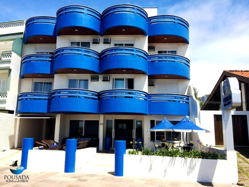 ein blau-weißes Gebäude mit einem Schirm davor in der Unterkunft Pousada Ilha dos Lobos in Torres